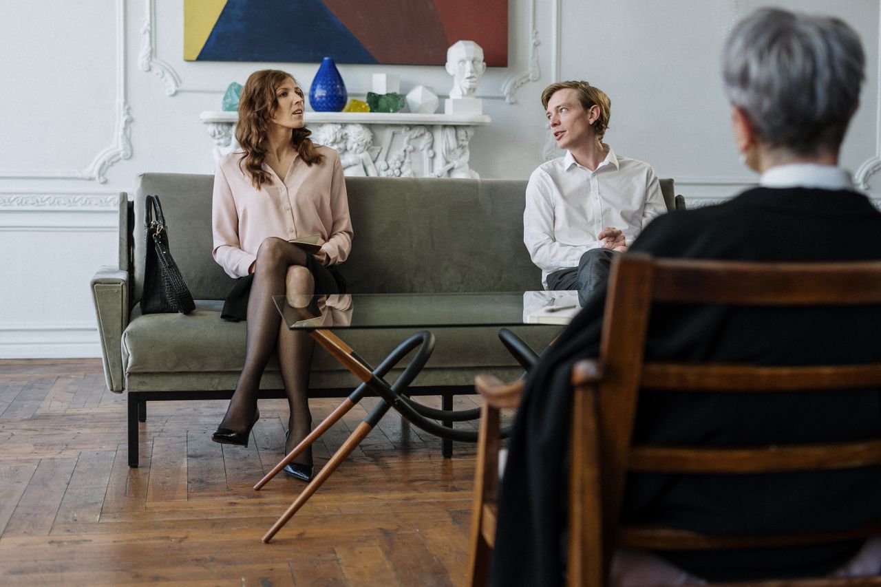 A couple having a discussion with a counselor in a modern office setting.