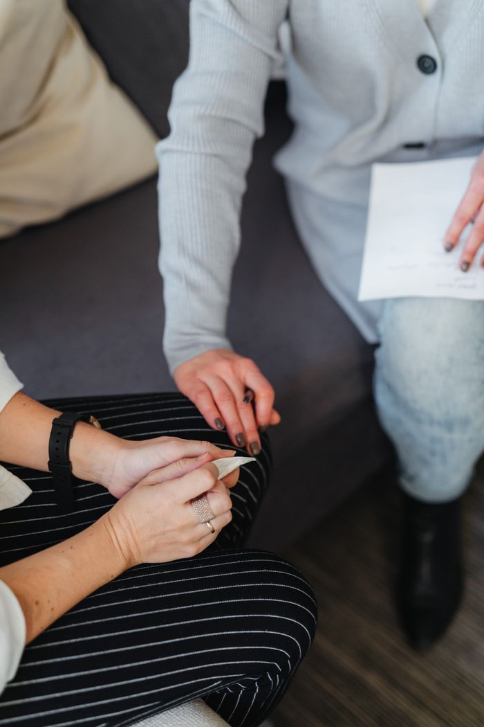 Close-up of two women sitting and holding hands, conveying trust and support.